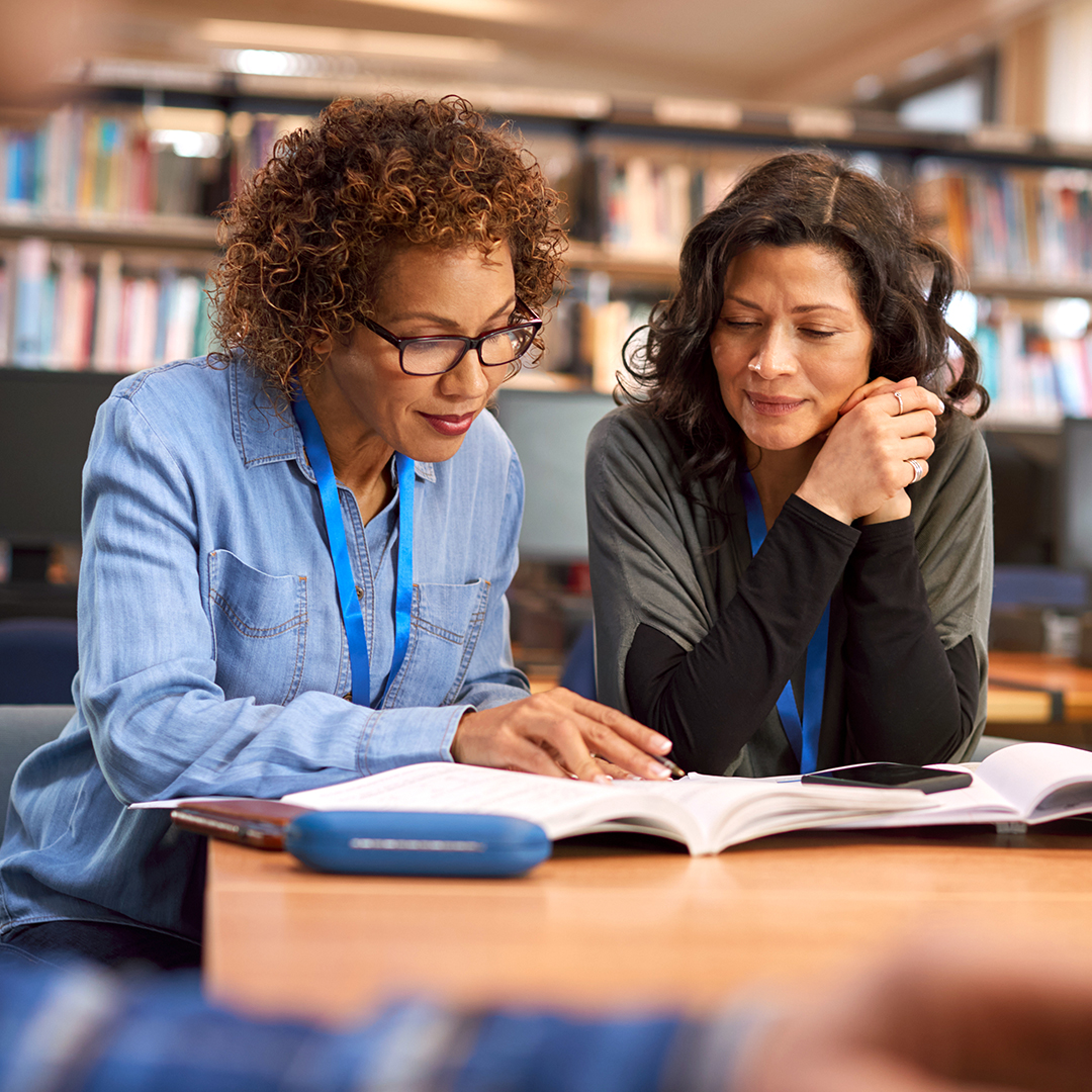 Two women in a library discussing implementation science research