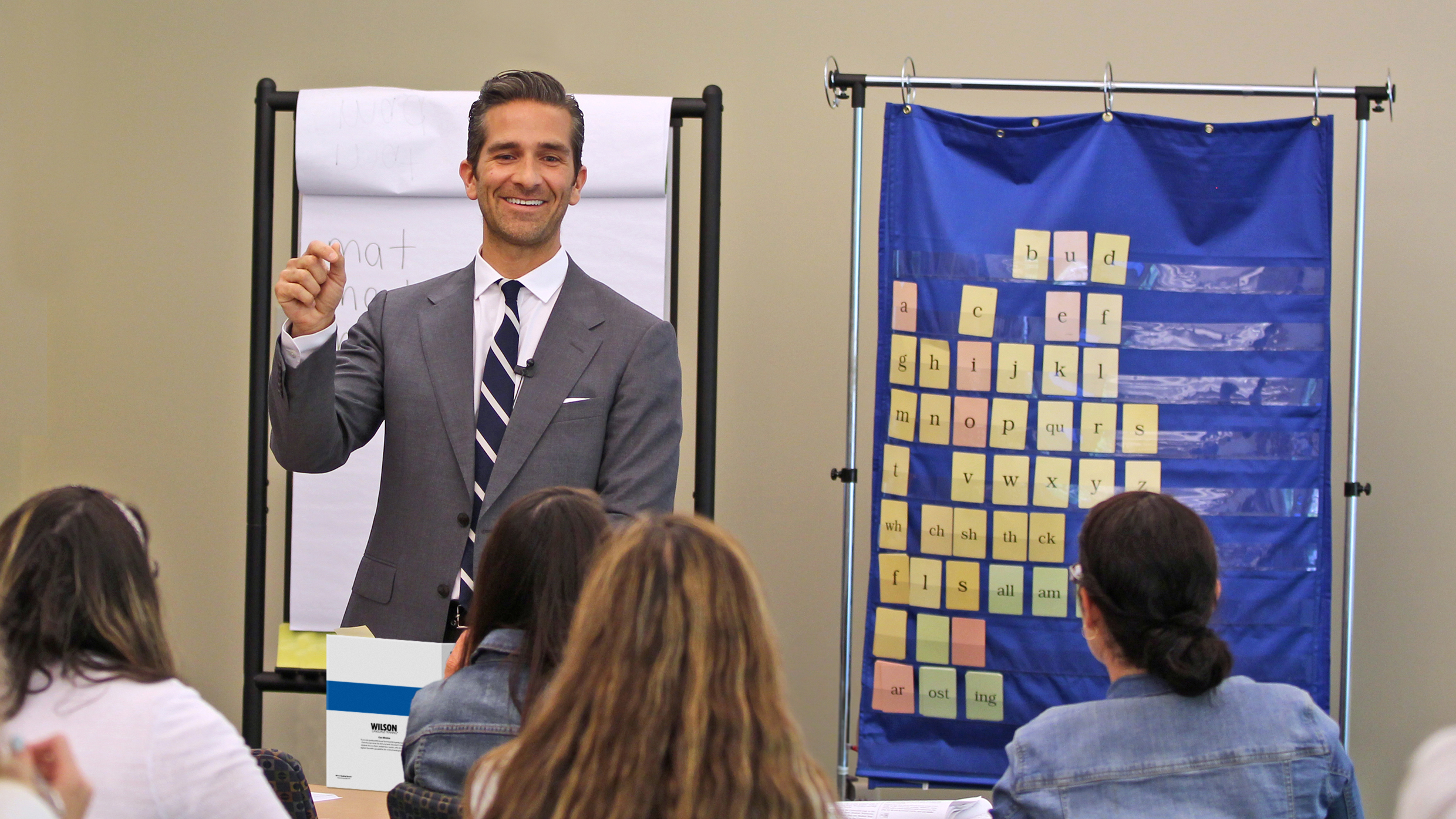 Instructor teaching Wilson Reading System® using alphabet chart and whiteboard.