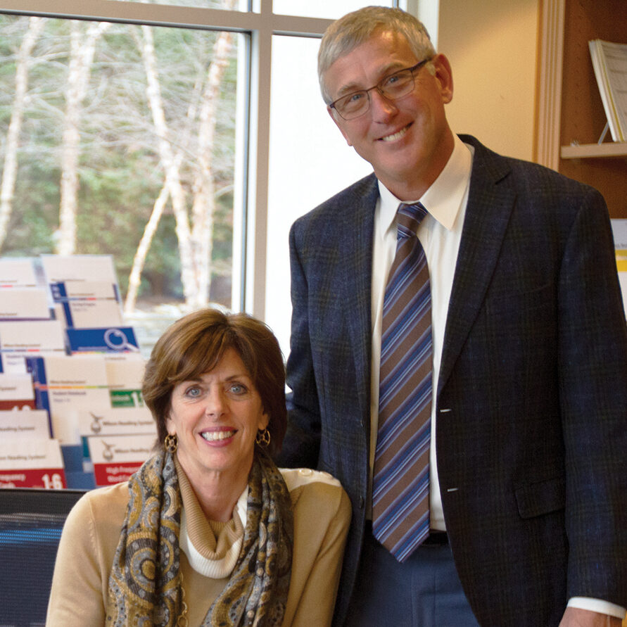 Company founders, a man and woman, smile in an office setting.