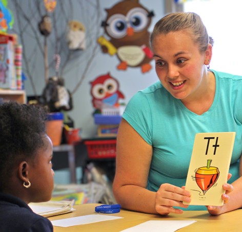 Teacher shows child flashcard with letter T and spinning top