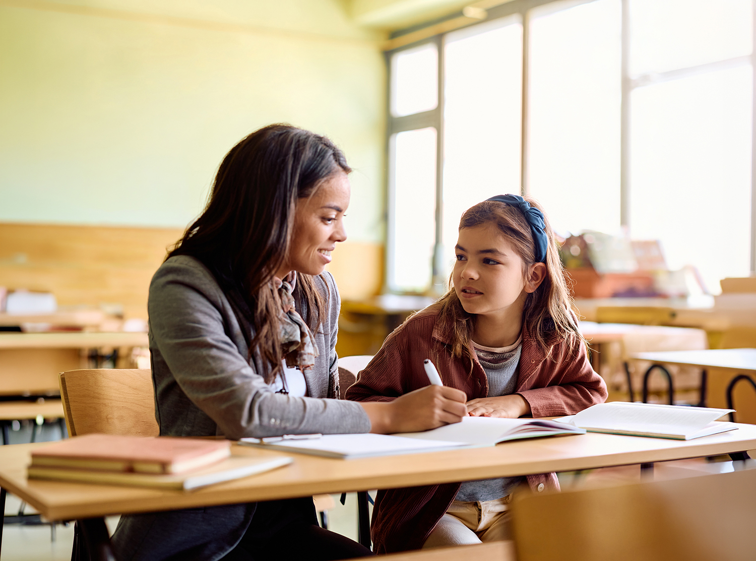 Teacher helping a student with schoolwork in a classroom.