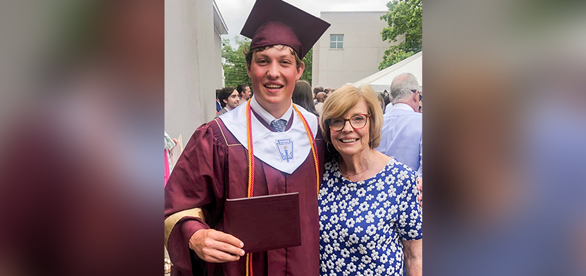 Young graduate in cap and gown with his proud grandmother at commencement.