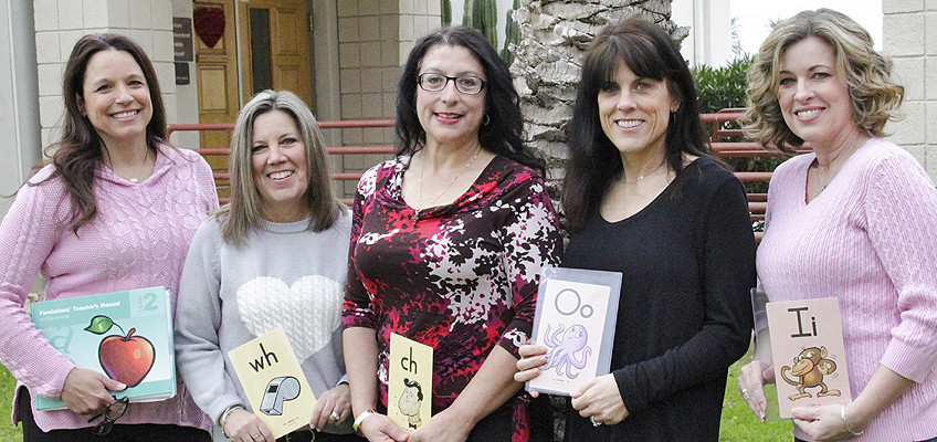 Five women teachers holding educational flashcards with letters and words