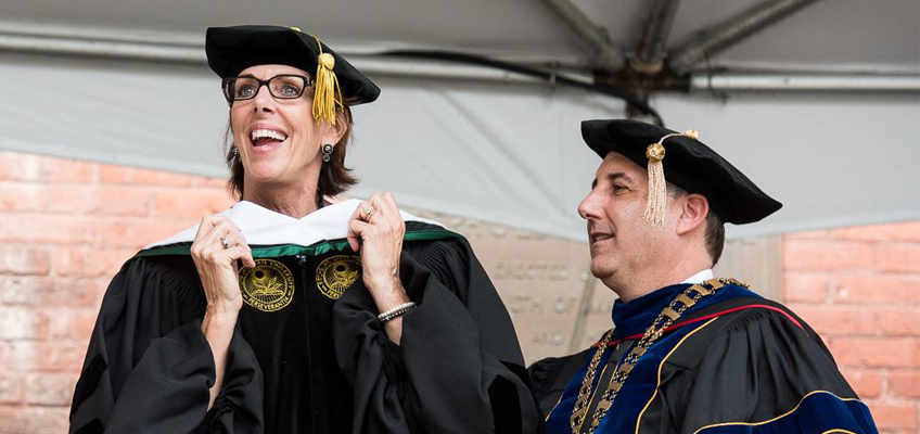 Barbara Wilson smiles in academic regalia at Fitchburg State University commencement.