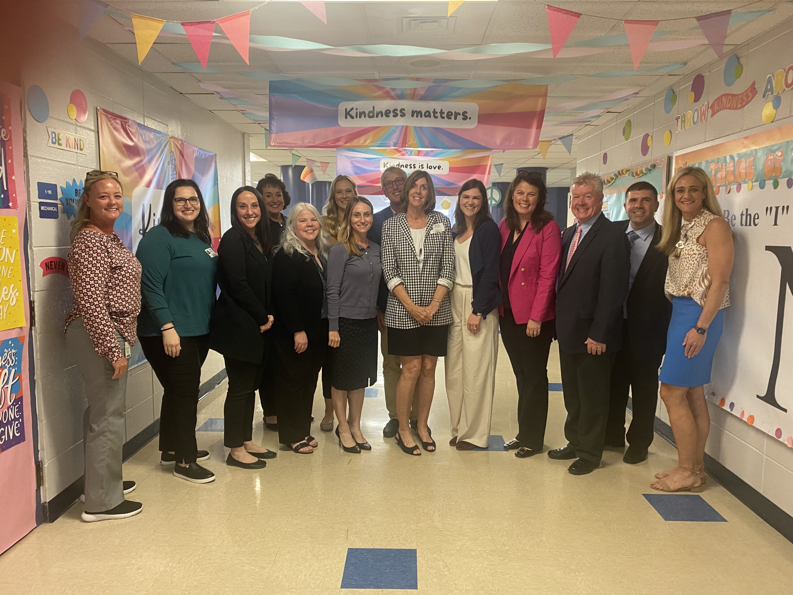 Group of educators in a school hallway with "Kindness matters" banner