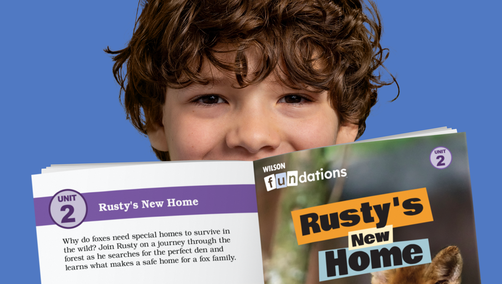 Young boy smiles holding "Rusty's New Home" Fluency Reader book