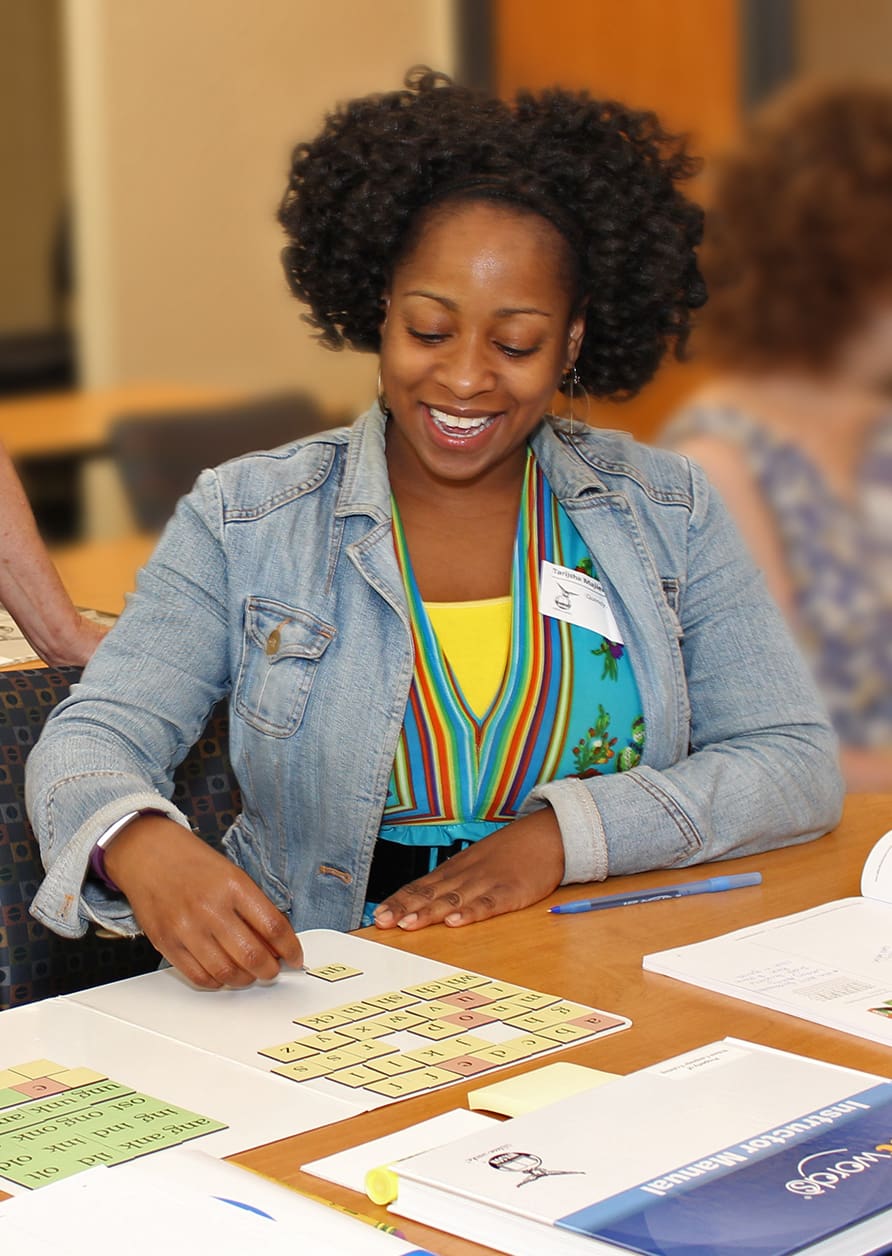 Woman teaching literacy using word tiles in a classroom setting.