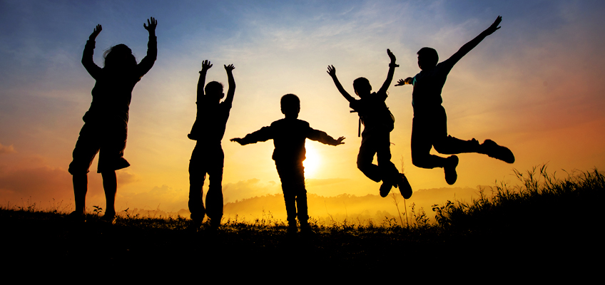 Silhouettes of five children jumping joyfully at sunset