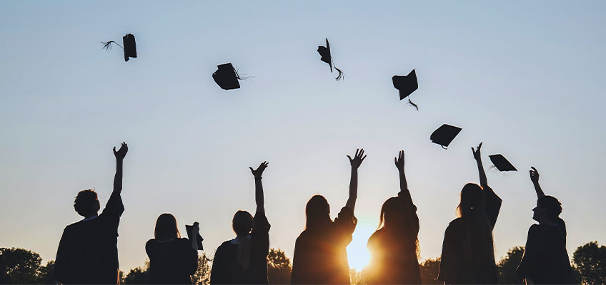Graduates in caps and gowns throwing hats in the air, symbolizing achievement and aiming high.