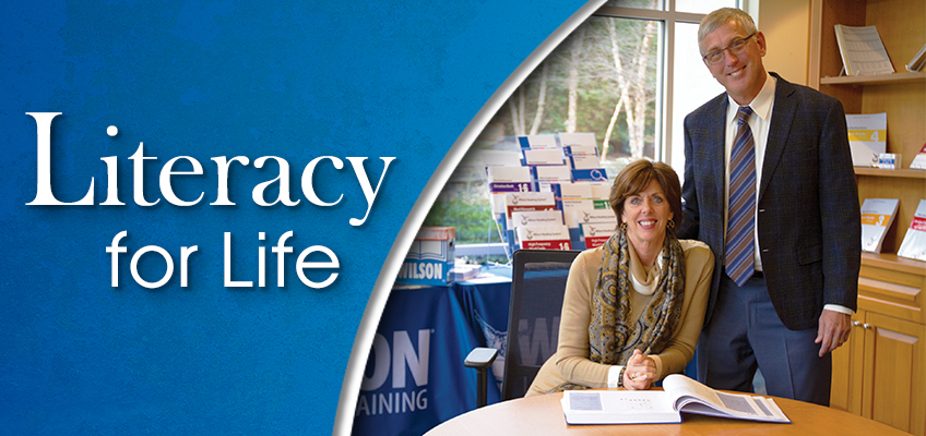 Literacy for Life: Two smiling adults in an office setting with books and educational materials