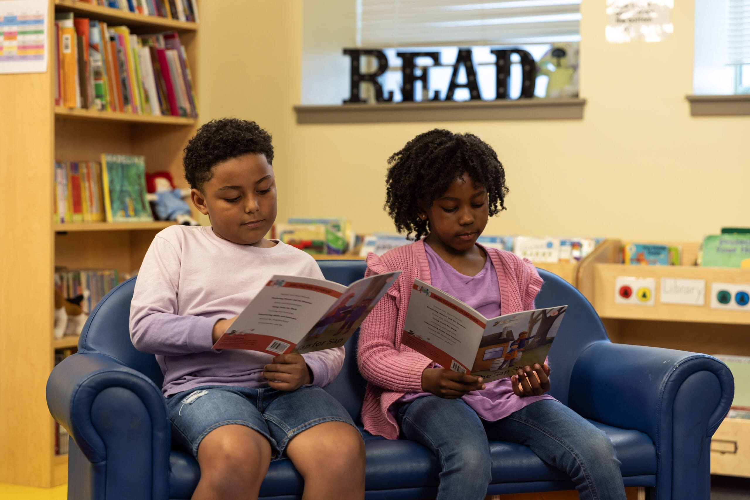 Two young students reading Fundations® readers in a library